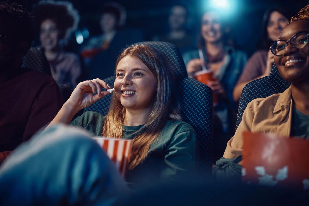 Happy teenage girl watching a film at the cinema