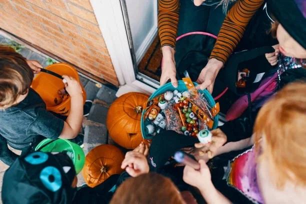 Image of someone handing out trick or treat sweets to kids. Six ways to ‘slash’ your Halloween spending this year