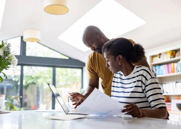 Image of a couple checking their finances and making payments on credit cards. Money Wellness partners with Capital One to help more people take control of their finances