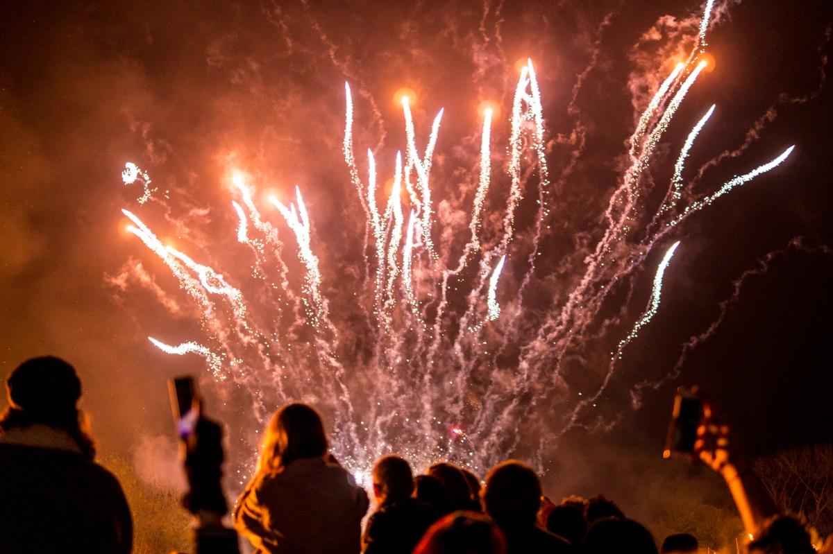 People celebrating bonfire night beneath a sky full of fireworks