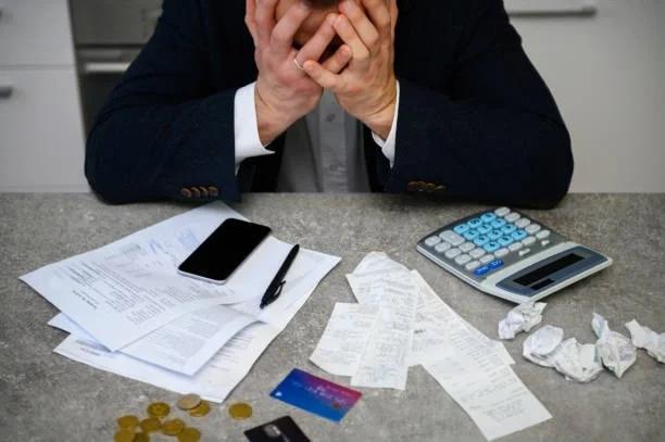 Image of someone looking stressed in front of a calculator and bills. Why your overdraft could be more dangerous than your credit card