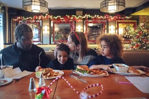 Image of a family out for a meal at Christmas with decorations in the background. All the places where kids eat free (or cheap) this Christmas 2025. Save on family meals over the festive break