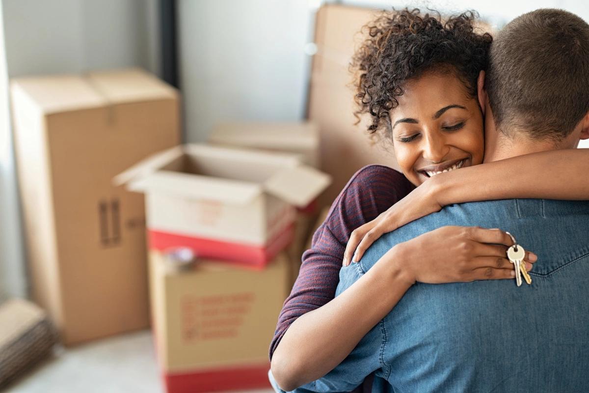 Two people hugging with unpacked boxes in the background