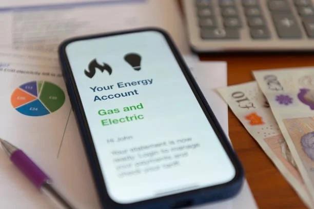 Image of a mobile phone with a gas and electricity online account open. Why electricity and gas prices are being separated – and what it could mean for your bills. Energy bill savings. Energy detb. Energy decoupling. Separating gas and electricity