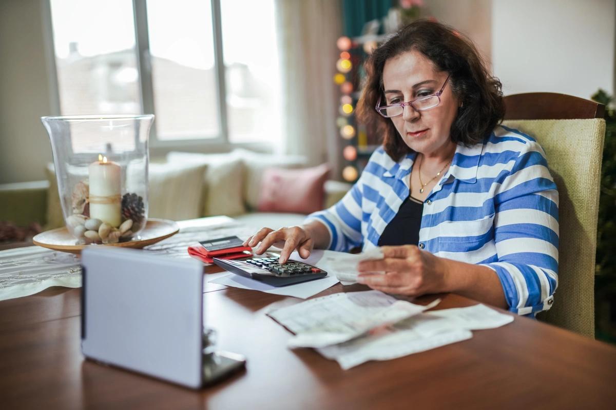 Woman sitting at a desk using a calculator to go through her receipts