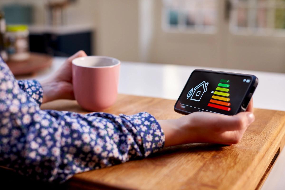 Close up of woman in kitchen holding smart energy meter measuring energy efficiency