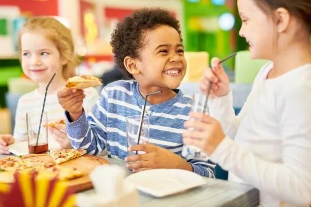 Image of kids eating a pizza. Half term meals made easy with kids eat free. 30 places to feed the kids for less this February 2026 half term school holidays