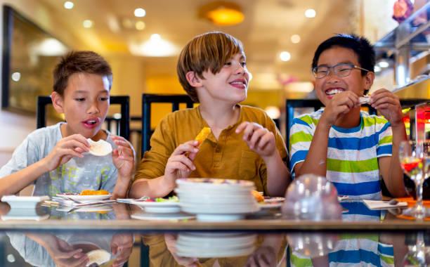Picture of kids eating in a restaurant. Where to find the ‘kids eat free this’ deals for summer 2025 .Complete list of all the kids eat free deals.