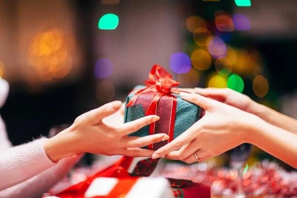 Image of someone handing someone a Christmas gift. 6 ways to make the most of your unwanted Christmas presents