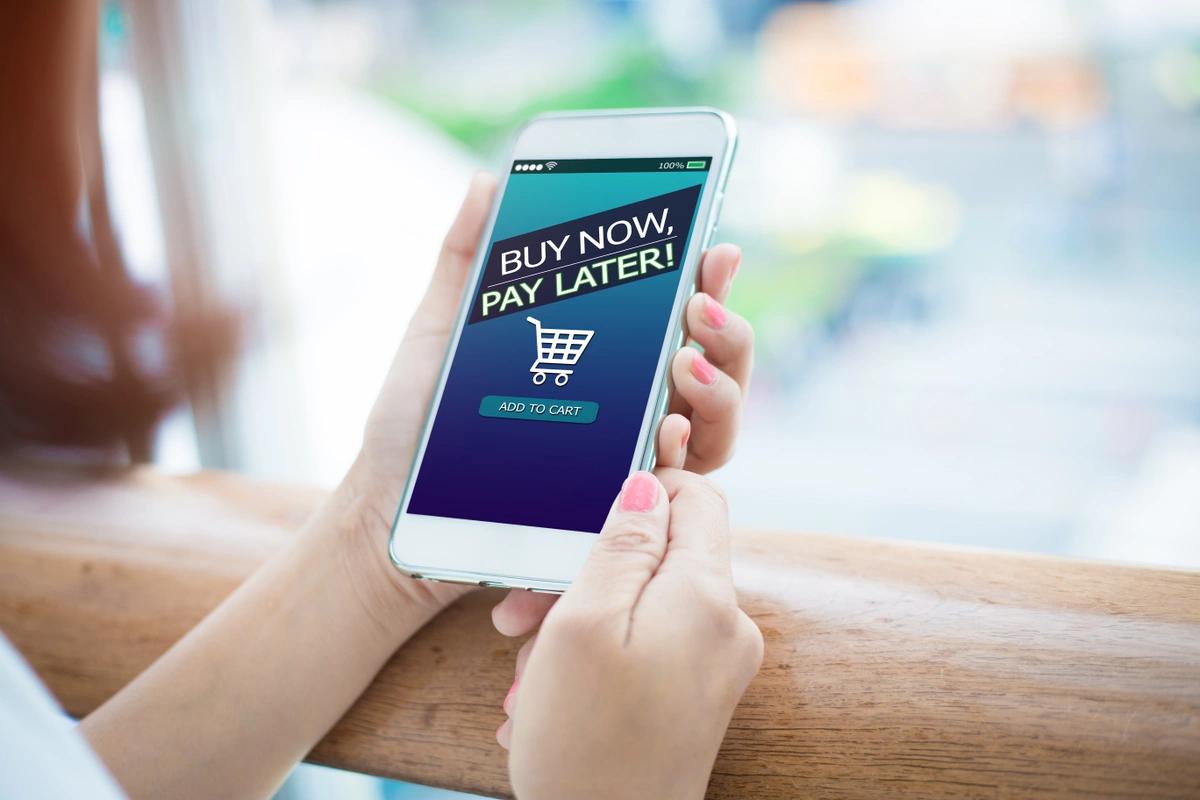 Close-up of someone holding a mobile phone with a buy now, pay later symbol on the screen